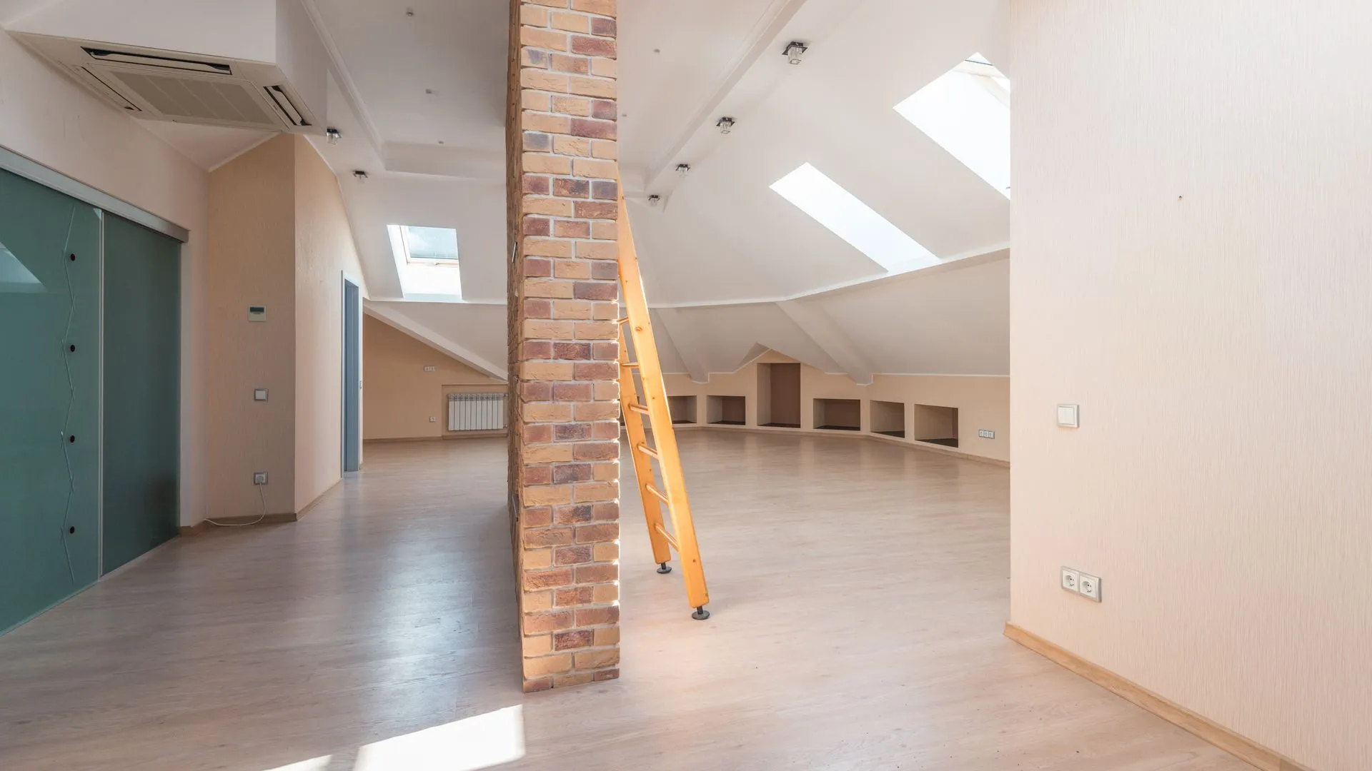 Világos tetőtéri loft téglapillérrel és a tetőablakokból érkező fénnyel